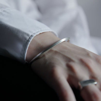 手首に沿うシルバー925のマットバングルのクローズアップ。フラットな断面と滑らかなカーブが分かるディテール写真。