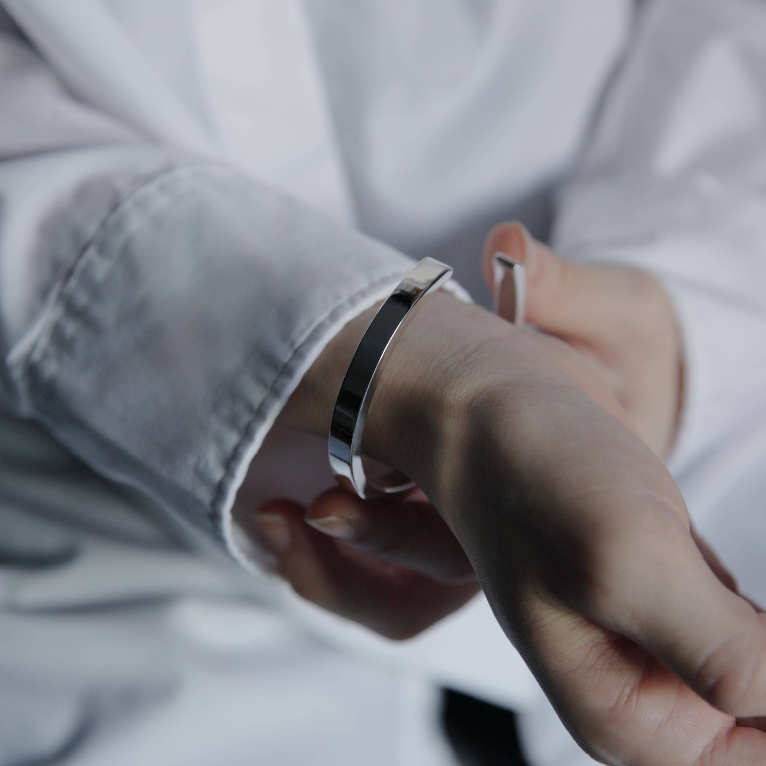 手元を包み込むように着用したシルバー925バングルとリングのアップ写真