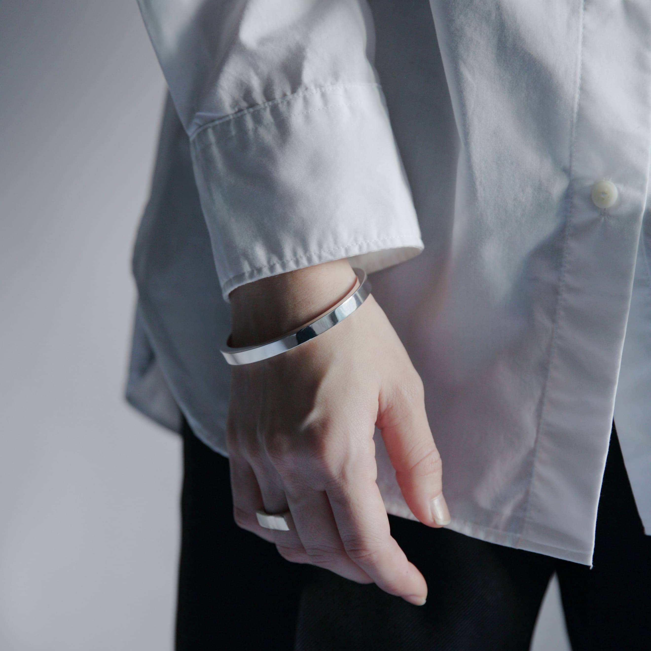 シンプルな装いに映えるシルバー925製バングルの着用イメージ、滑らかな鏡面仕上げのディテール