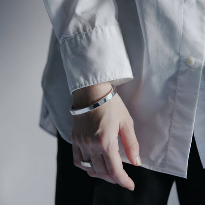 シンプルな装いに映えるシルバー925製バングルの着用イメージ、滑らかな鏡面仕上げのディテール