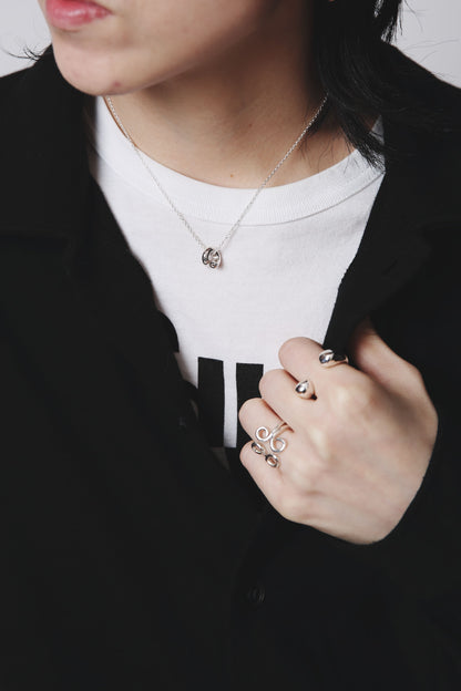 白Tシャツに重ねたシルバー925のペンダントネックレスと、個性あるリングのコーディネート。洗練された曲線が生み出す造形美が印象的。