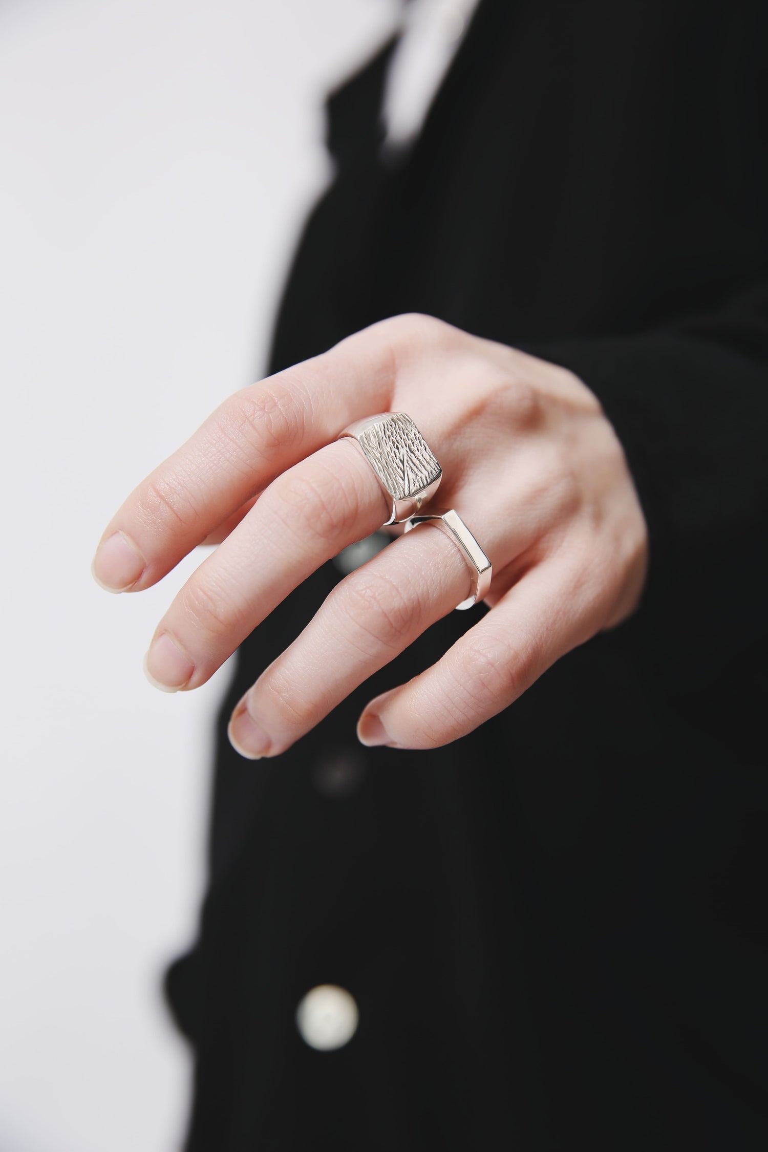 表面に独特のテクスチャーを施したシグネットリングと、シャープな細身のリングを重ね着け。黒の衣装に映えるシルバー925のモダンな手元。