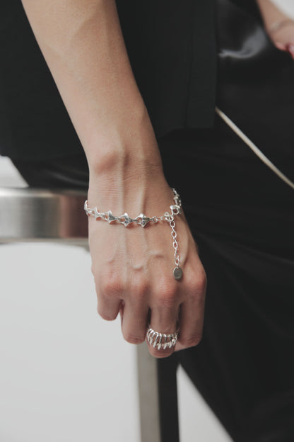 イチョウの葉のような独特な形状のシルバーパーツが連なるブレスレット。手首に沿って美しくフィットし、控えめな存在感で上品な印象を与える。