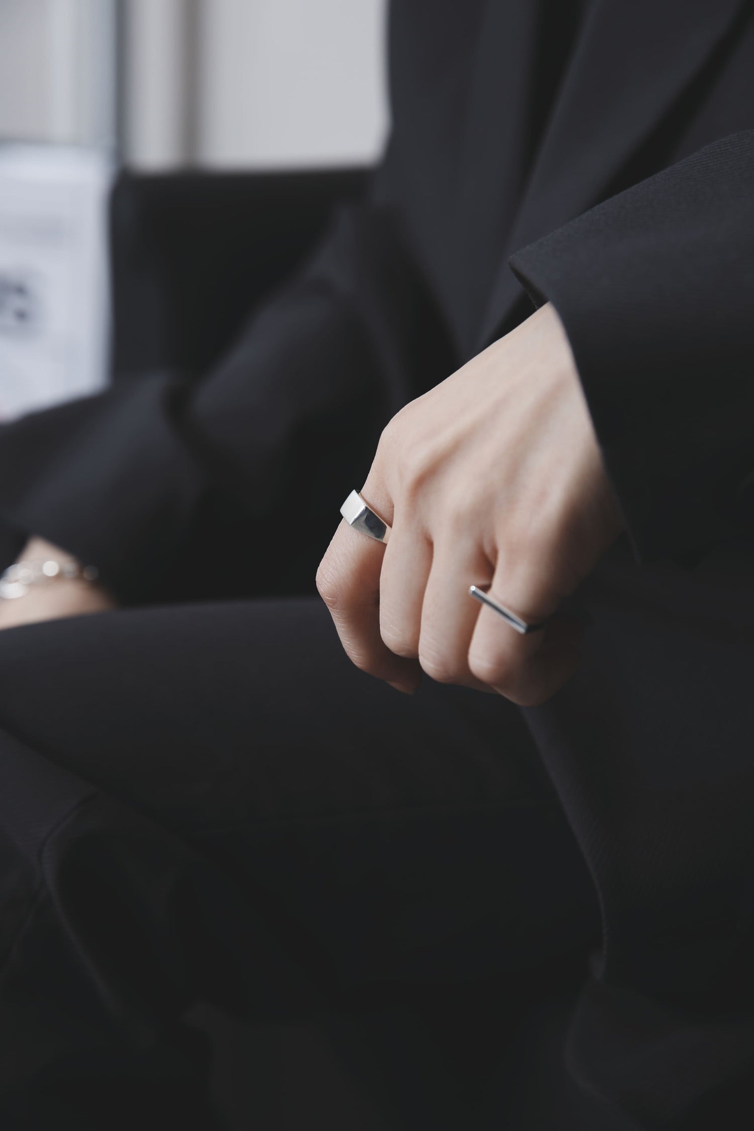 袖口から覗く指にシルバーのシグネットリングとバーリングを着用。無機質な輝きがブラックコーディネートに溶け込み、モードな雰囲気を強調している。