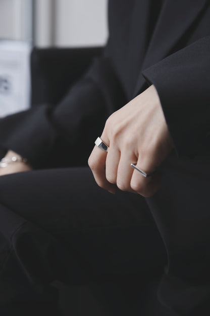 袖口から覗く指にシルバーのシグネットリングとバーリングを着用。無機質な輝きがブラックコーディネートに溶け込み、モードな雰囲気を強調している。