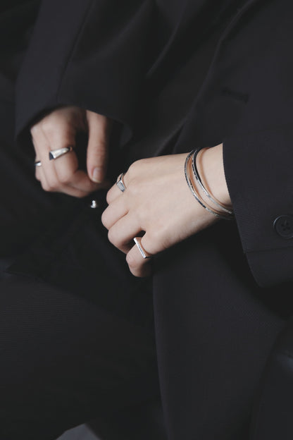 ブラックスーツに合わせたシルバー925細身バングル2本重ね付けの着用イメージ（リングとのコーディネート）
