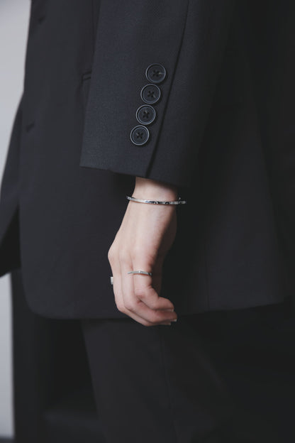 ブラックスーツから伸びる手首に、さりげなく主張するシルバーバングルと、繊細なディテールのリングがセットされたスタイリング。
