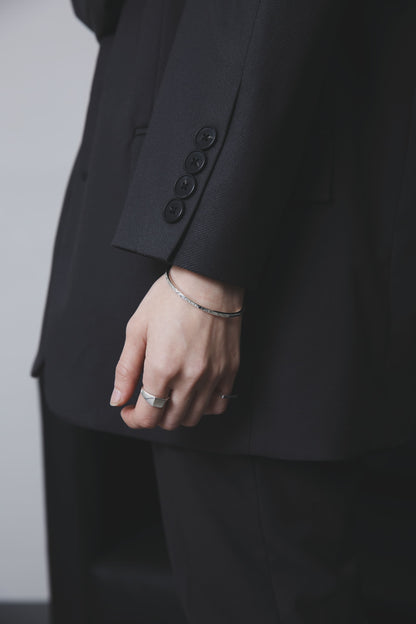 同様の角度から、手を自然に下ろした状態で撮影。バングルとリングが光を受けて控えめに輝き、洗練された手元を演出している。