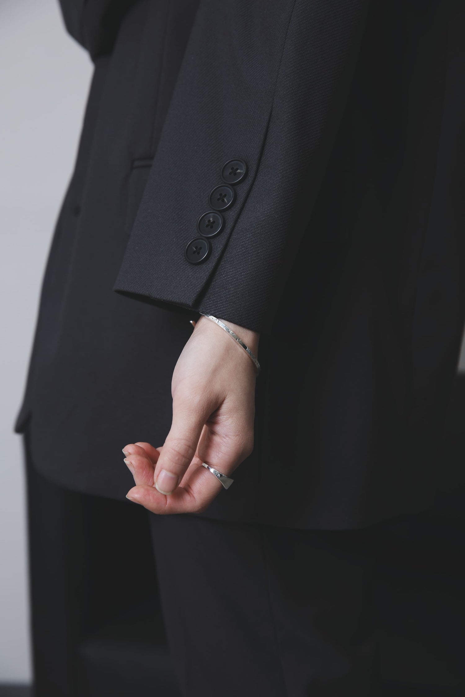 指先をやや内側に向けた構図で、バングルとリングの彫り模様や質感が強調され、クラフト感が伝わるショット。