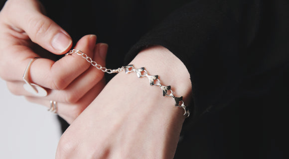 イチョウ型のパーツが連なるシルバーブレスレットを着用する様子。手元で輝く繊細なディテール。