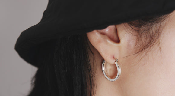シンプルな円形フープピアスを着けた横顔。ブラックハットと合わせたスタイリング。