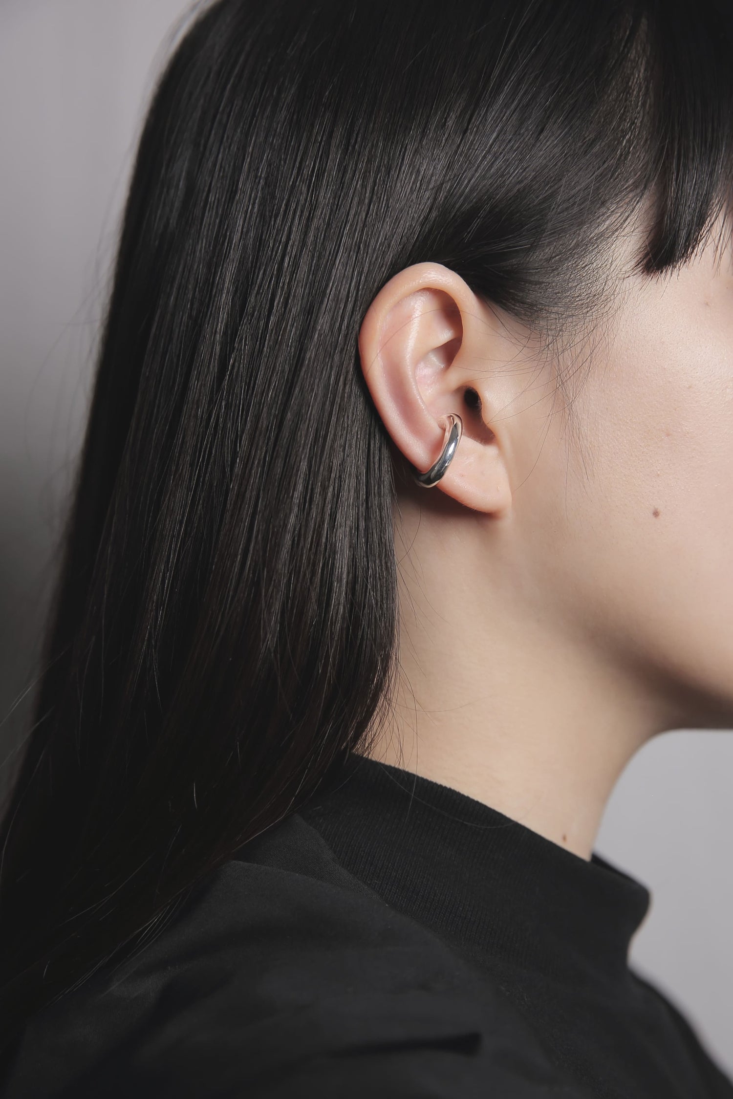 耳の軟骨部分に装着したシルバー925のイヤーカフ。肌馴染みの良い曲線的なフォルムが、顔まわりにモダンで洗練された印象を与えます。