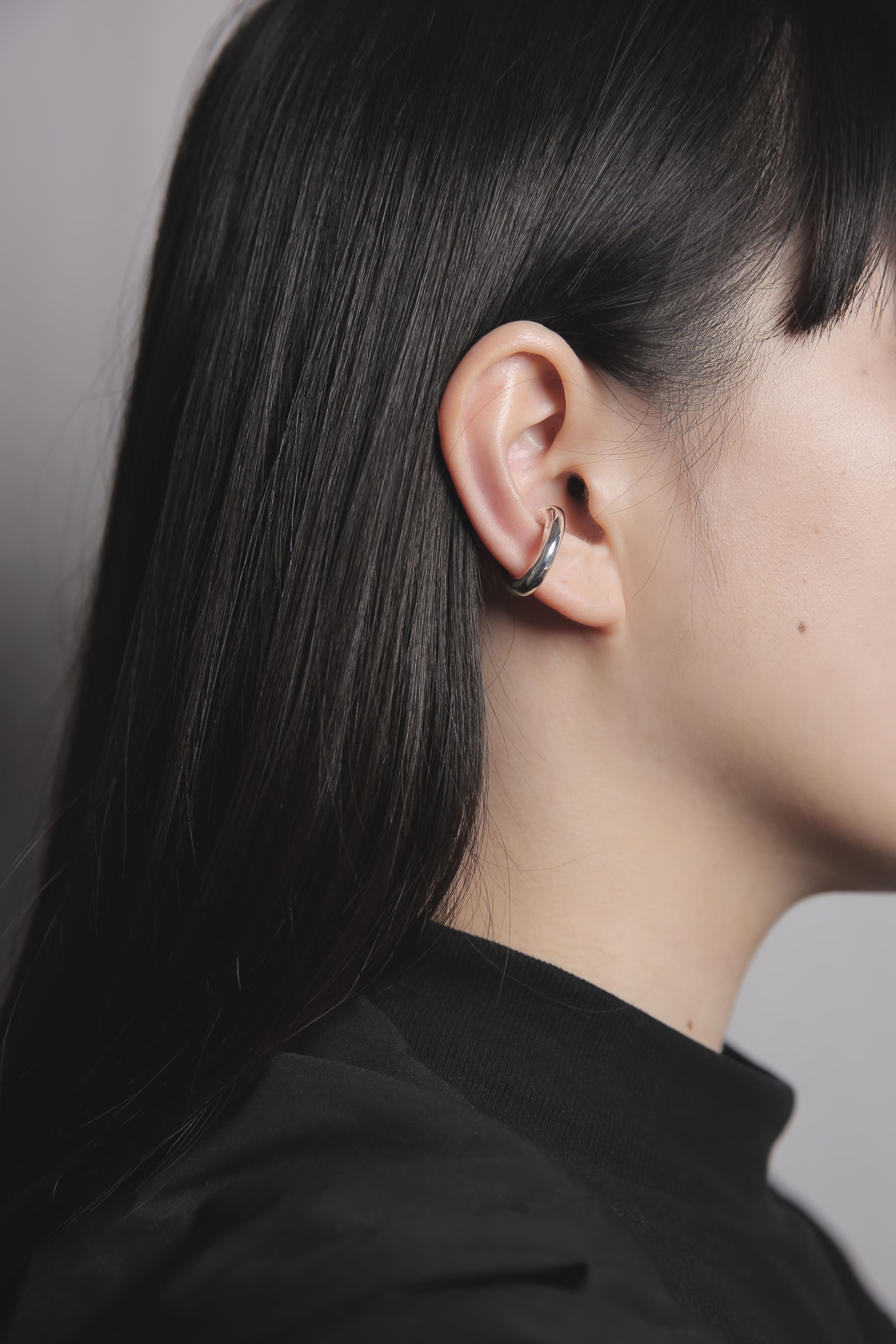 耳の軟骨部分に装着したシルバー925のイヤーカフ。肌馴染みの良い曲線的なフォルムが、顔まわりにモダンで洗練された印象を与えます。
