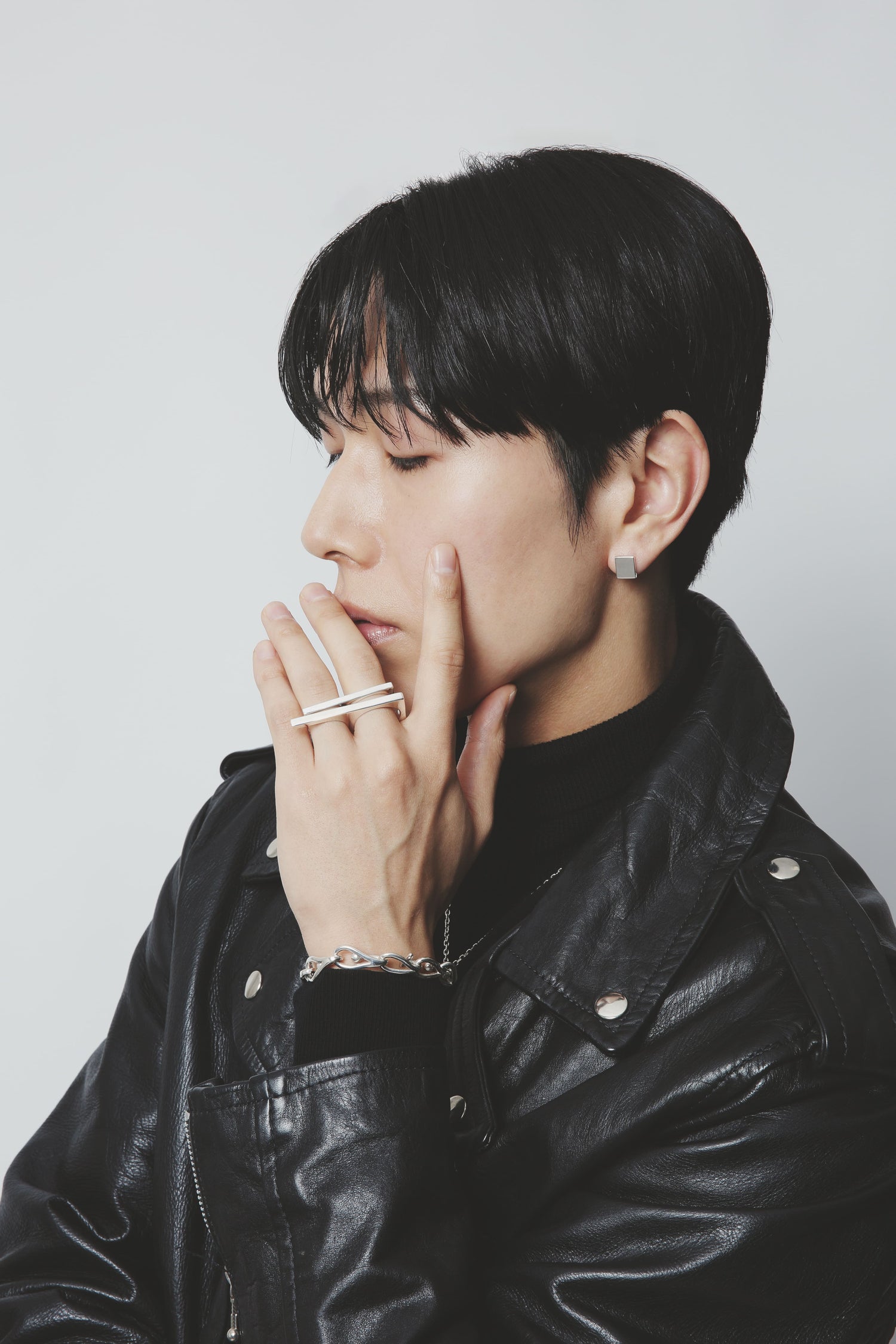 黒のレザージャケットを羽織った男性が、シルバー925のスクエアピアスと個性的なダブルラインリングを着用しているカット。ユニセックスに楽しめるシルバー925素材の魅力を引き出した、モードな雰囲気のスタイリング。