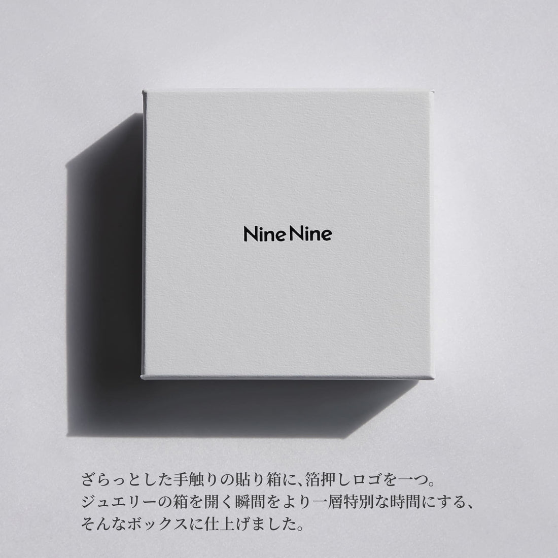 Nine Nineのロゴが中央に箔押しされた、さらりとした質感のホワイトボックス。やわらかな光と影が落ちるミニマルなパッケージイメージ。