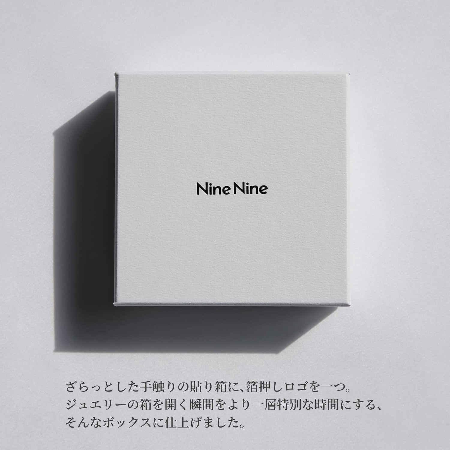 Nine Nineのロゴが中央に箔押しされた、さらりとした質感のホワイトボックス。やわらかな光と影が落ちるミニマルなパッケージイメージ。