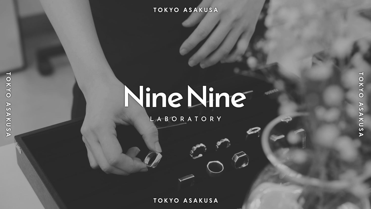 「Nine Nine LABORATORY」のロゴが中央に配置されたモノクロのビジュアル。浅草のアトリエでシルバーリングをディスプレイに並べる様子が写っており、背景には「TOKYO ASAKUSA」の文字が繰り返し表示されている。